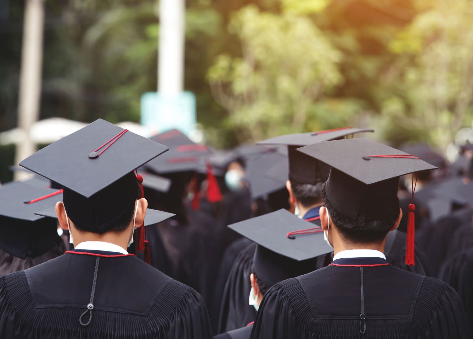 Graduates in black robes and caps at a university graduation ceremony.