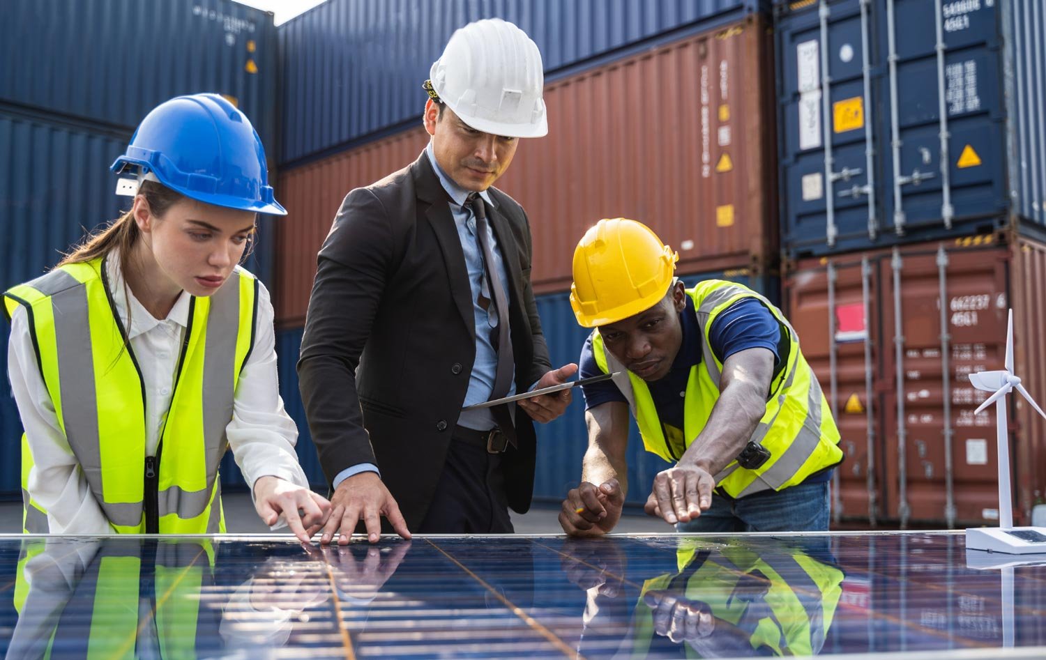 A diverse group of engineers analyzing a solar panel at a shipping container site.