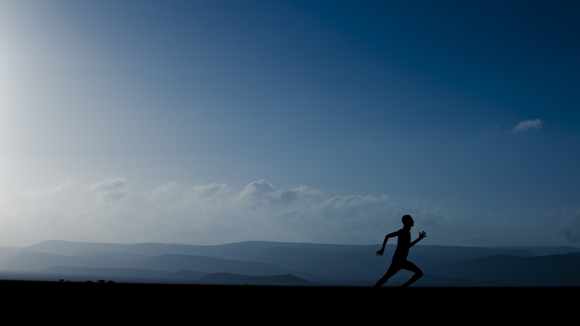 Silhouette of runner with blue sky in the background