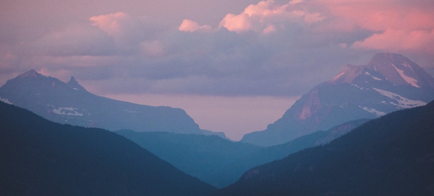 A cotton candy sky behind a mighty mountainscape