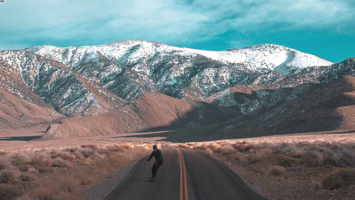 Mountain landscape with a skateboarder on a road 