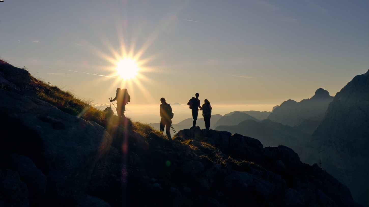 A group of people hiking a mountain at sunrise