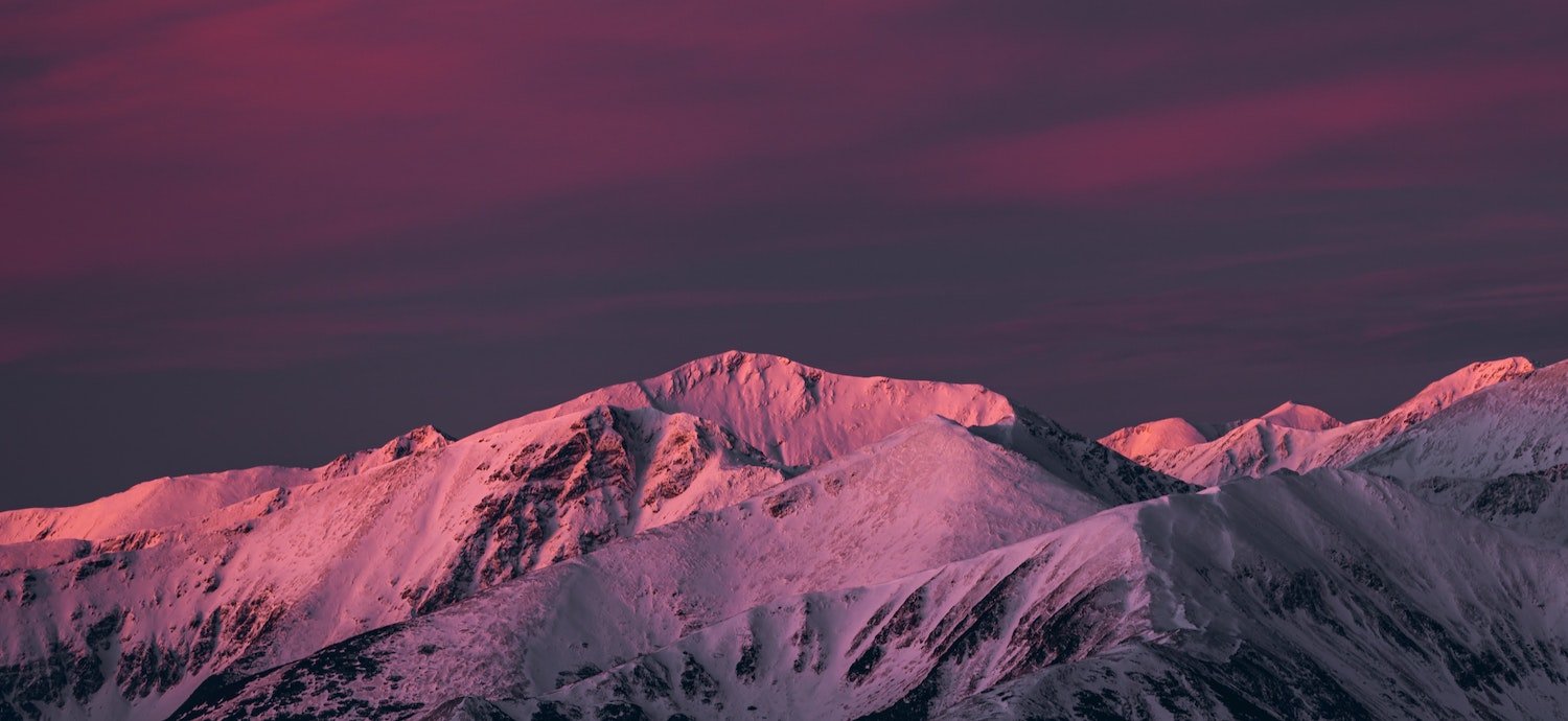 Vibrant pink sunset over snowy mountains