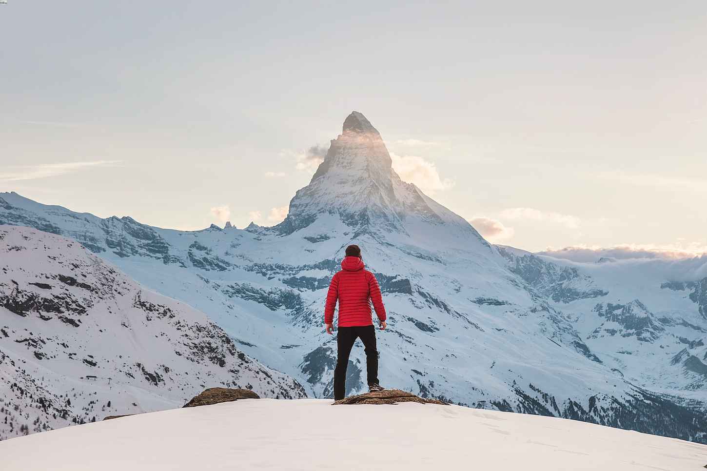 Man standing on snowy mountain, looking at mountain ahead