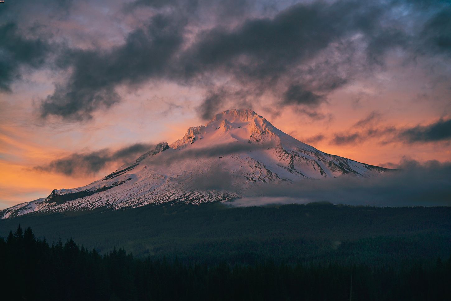 Sun setting behind a cloudy mountain peak