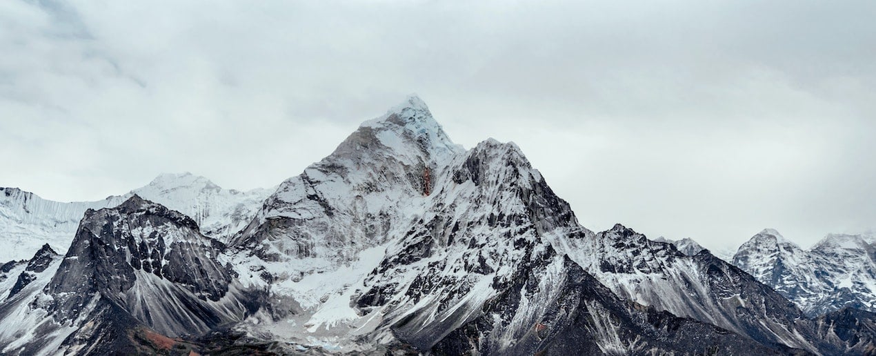 Cloudy sky set behind a snow covered mountain