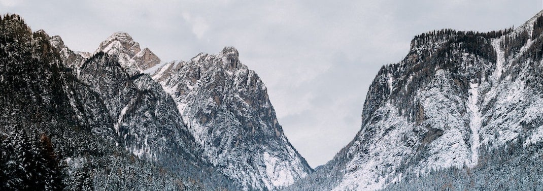 Twin mountain peaks covered with trees and snow