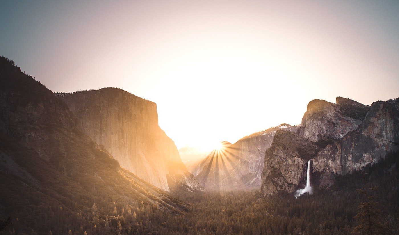 Bright sunrise peaking out from behind a mountain peak