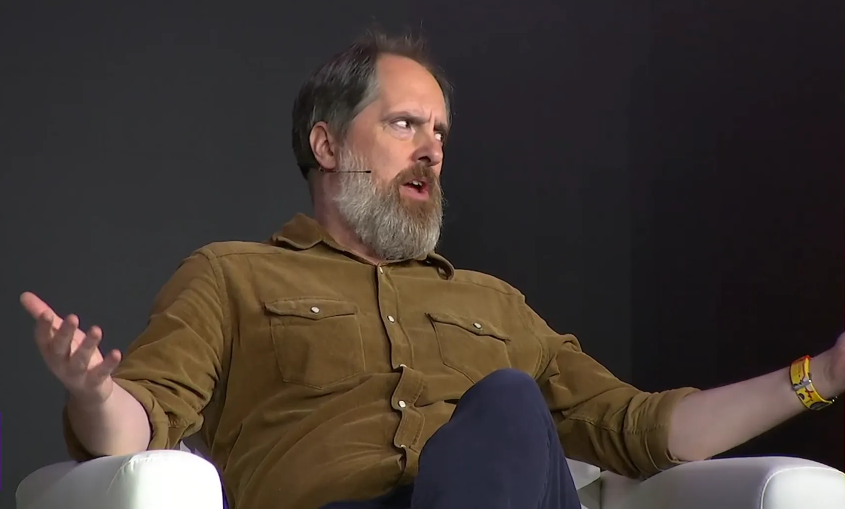 Bearded actor Brandon Hunt puts his arms out wide while sitting and talking to the audience