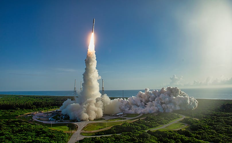ロケット発射、打ち上げ時の轟音と煙。青い空と海を背景に、緑豊かな発射場