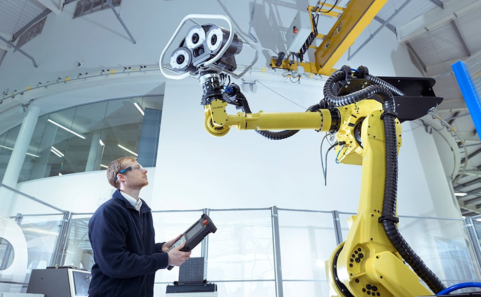 工場でロボットアームを操作する技術者。