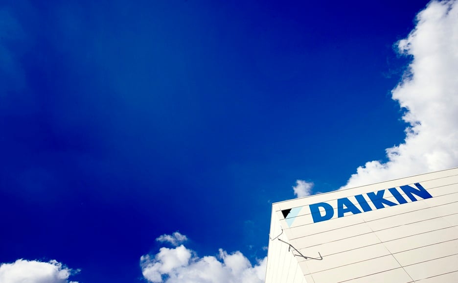 Daikin logo on side of building against blue sky and white clouds.