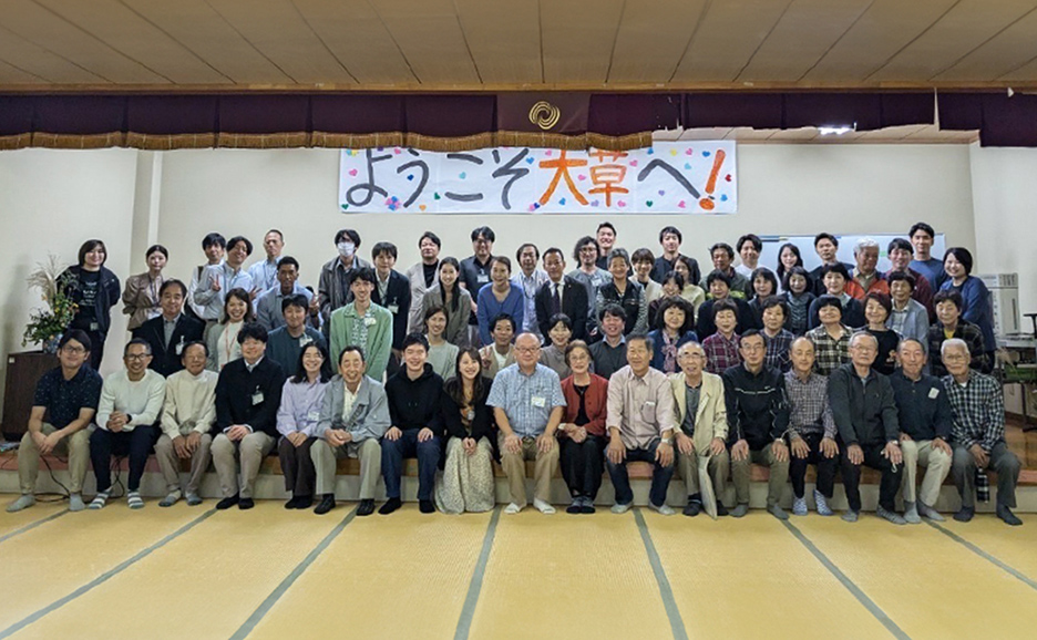 ようこそ大草へ!と書かれた横断幕の前で撮られている、50名ほどの集合写真