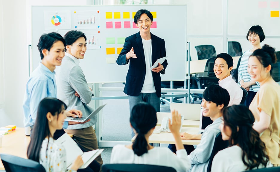 オフィス環境でのビジネスミーティング 多くの若い社員が和やかにコミュニケーションしている