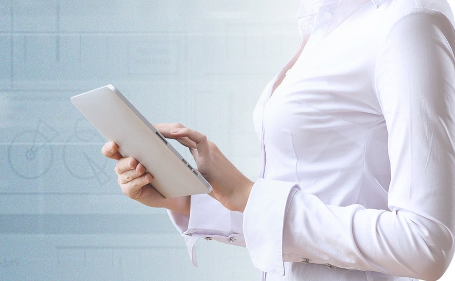 白いシャツを着た女性が、未来的な背景の前でデジタルタブレットを使用している。