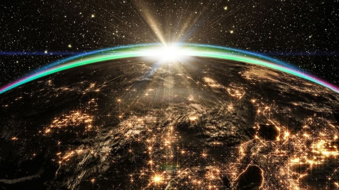 Imagem da Terra com luzes brilhantes nas cidades durante a noite e um pôr do sol radiante ao fundo, destacando a beleza do planeta.