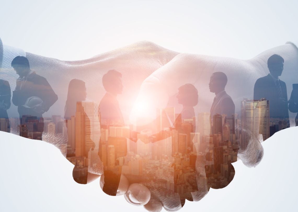 Imagem que representa a conexão e o relacionamento profissional, simbolizada por um aperto de mãos em meio a silhuetas de pessoas e uma cidade ao fundo. Ideal para temas relacionados a negócios, parcerias e networking.