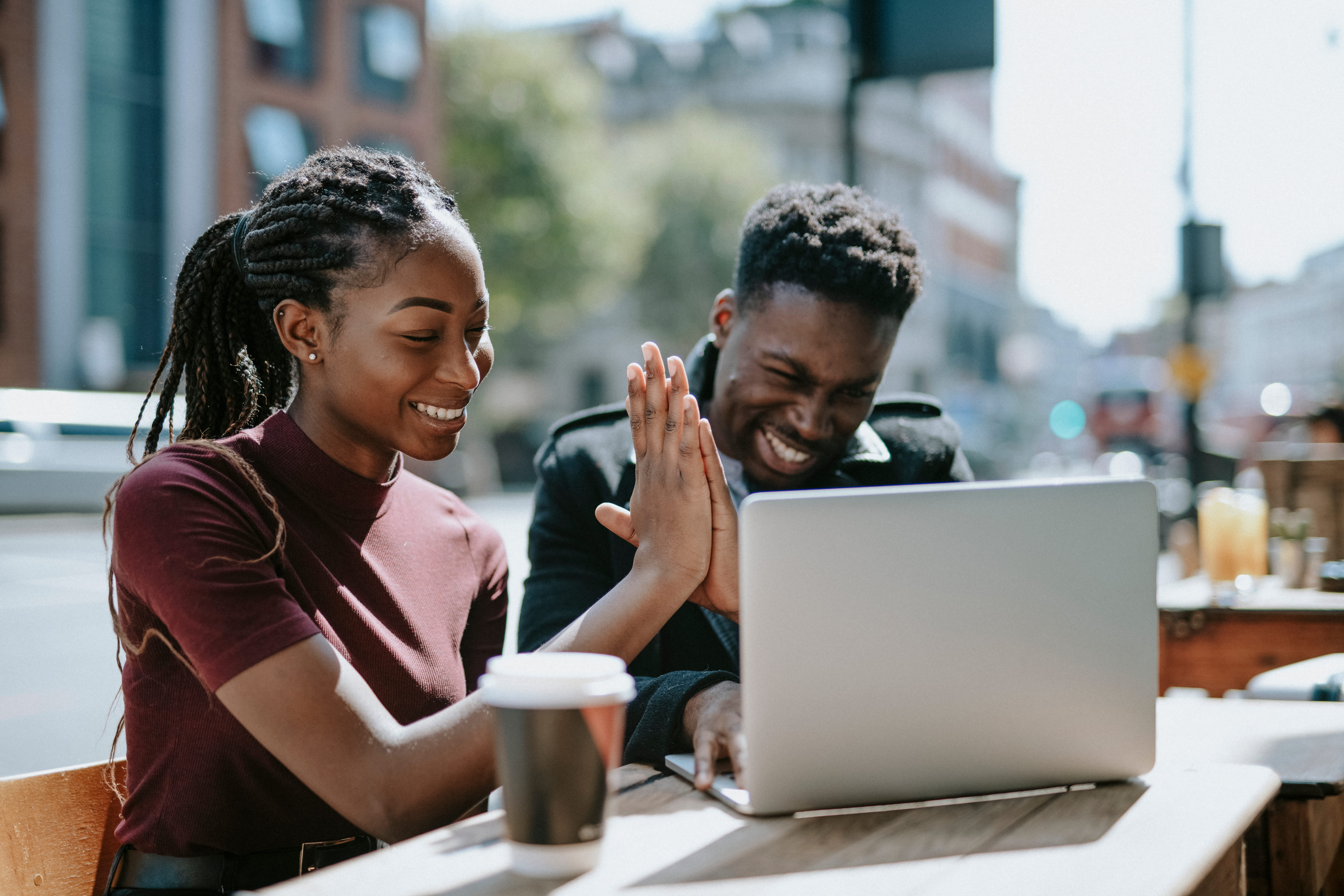 Two people working at a computer and sharing a high five