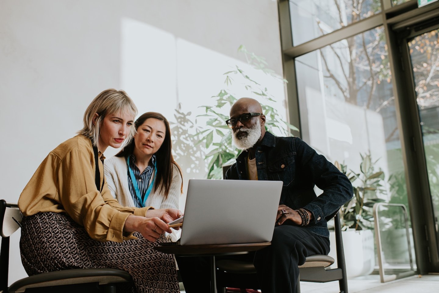 Two women and a man sitting together looking at a laptop