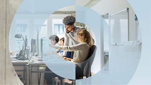 Two co-workers in an office looking at The Pulse of Work in 2025 report on a desktop computer.