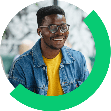 Hombre sonriendo en su ordenador, lleva auriculares mientras asiste a una videoconferencia en público.