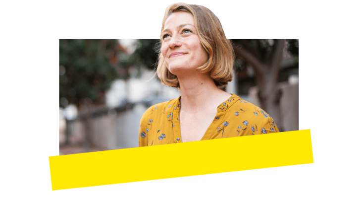 Woman outside in the sun looking up and smiling happily. 