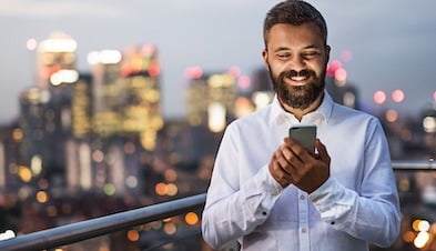 Man videoconferencing on mobile phone with city skyline in background