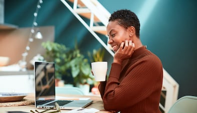 Creative professional with laptop smiling and drinking coffee