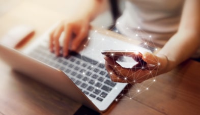 Teletrabajador que usa un portátil y un teléfono móvil con un gráfico de red superpuesto