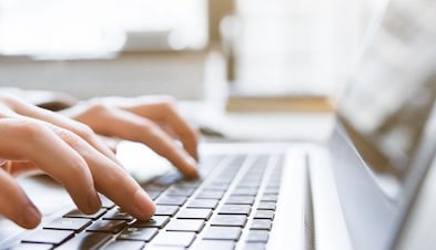 Closeup of someone typing on their laptop while working remote