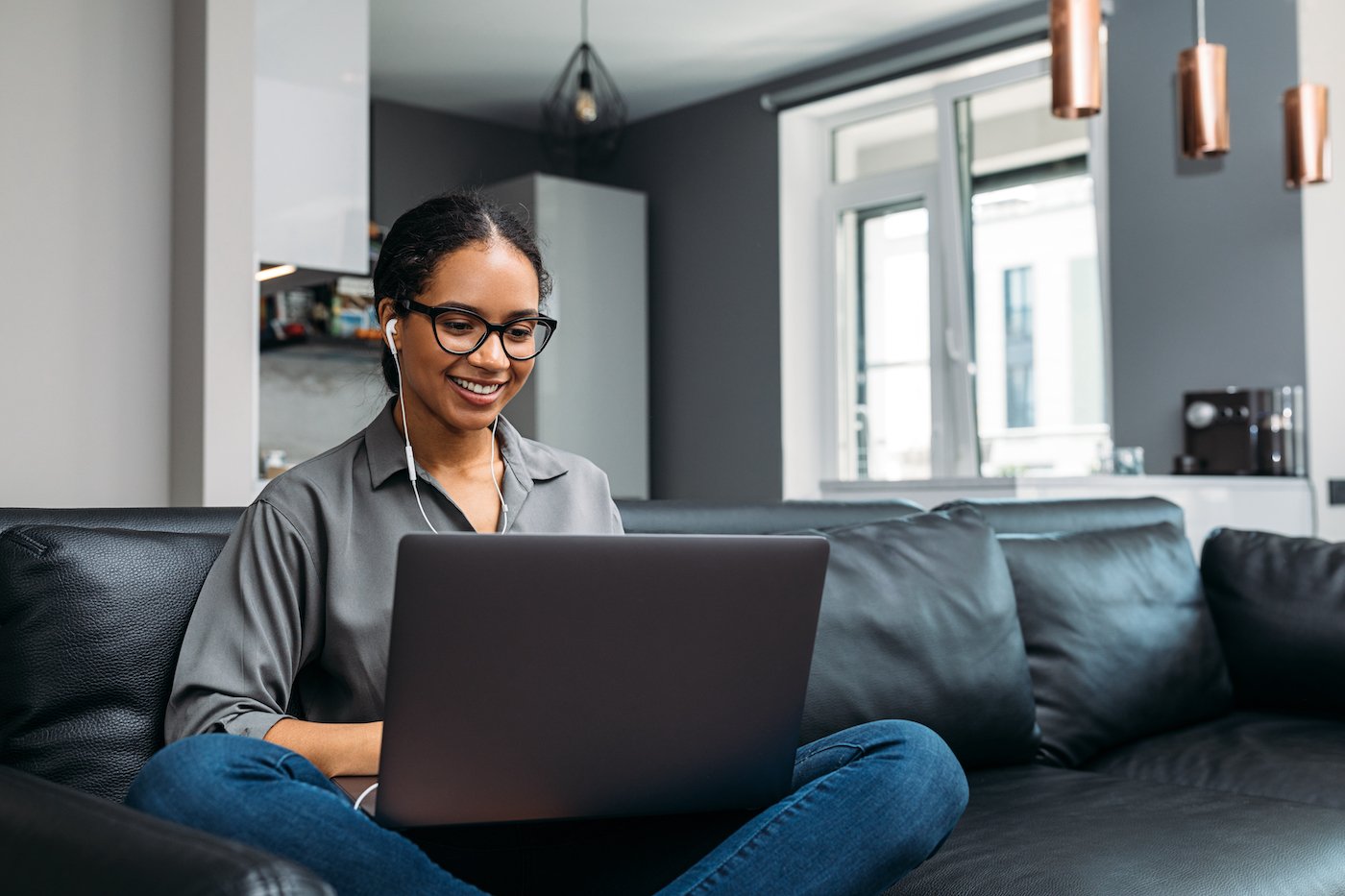 Woman working on living room couch with her laptop, protected by cyber security technology like hashing and zero trust security