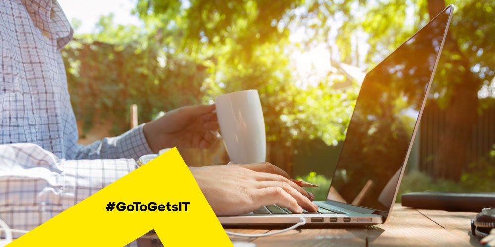 Close up image of a remote professional’s hands working at a laptop in a backyard setting, highlighting the need for remote support