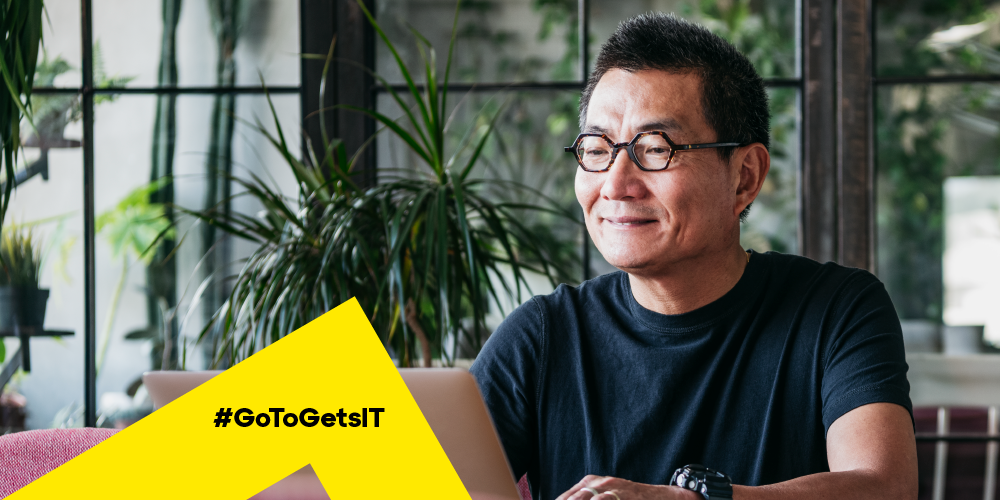 Man working at a laptop in a plant-filled room learning about how to fix DNS errors