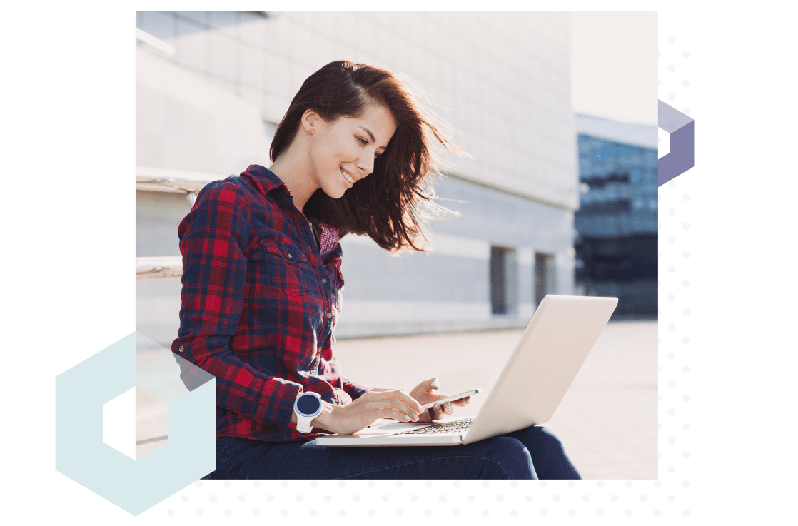College student sitting in front of the school building getting online help with setting up her laptop.