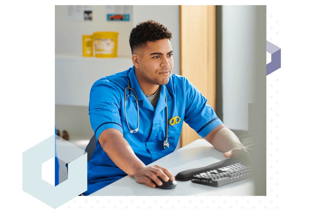 Doctor sitting at a computer desk in a hospital, working with an IT technician using remote control.
