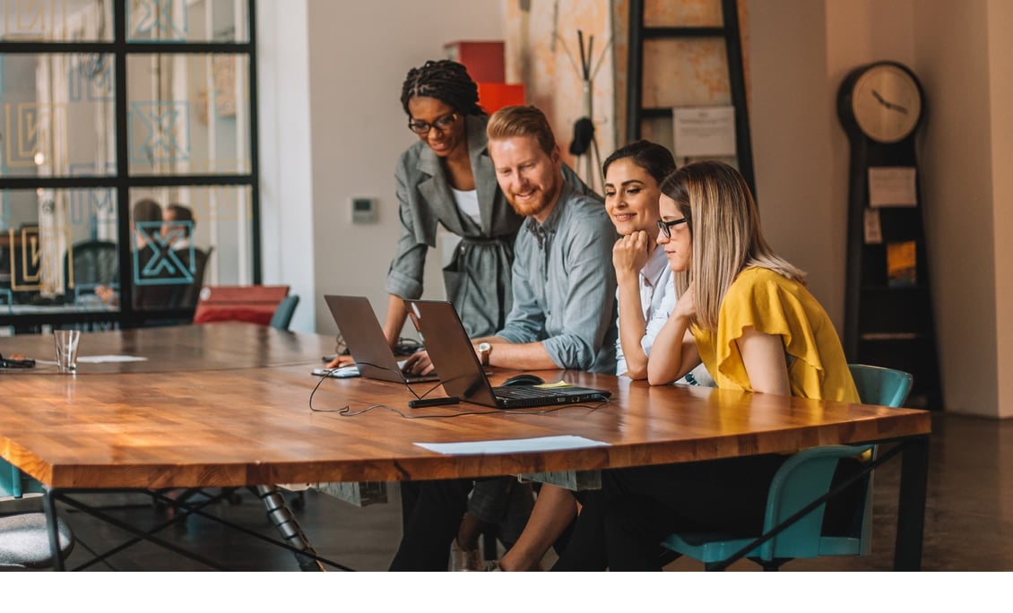 Wie KI Unternehmen verändern kann: Eine Gruppe von Personen sitzt um ihre Laptops herum und führt ein Gespräch.