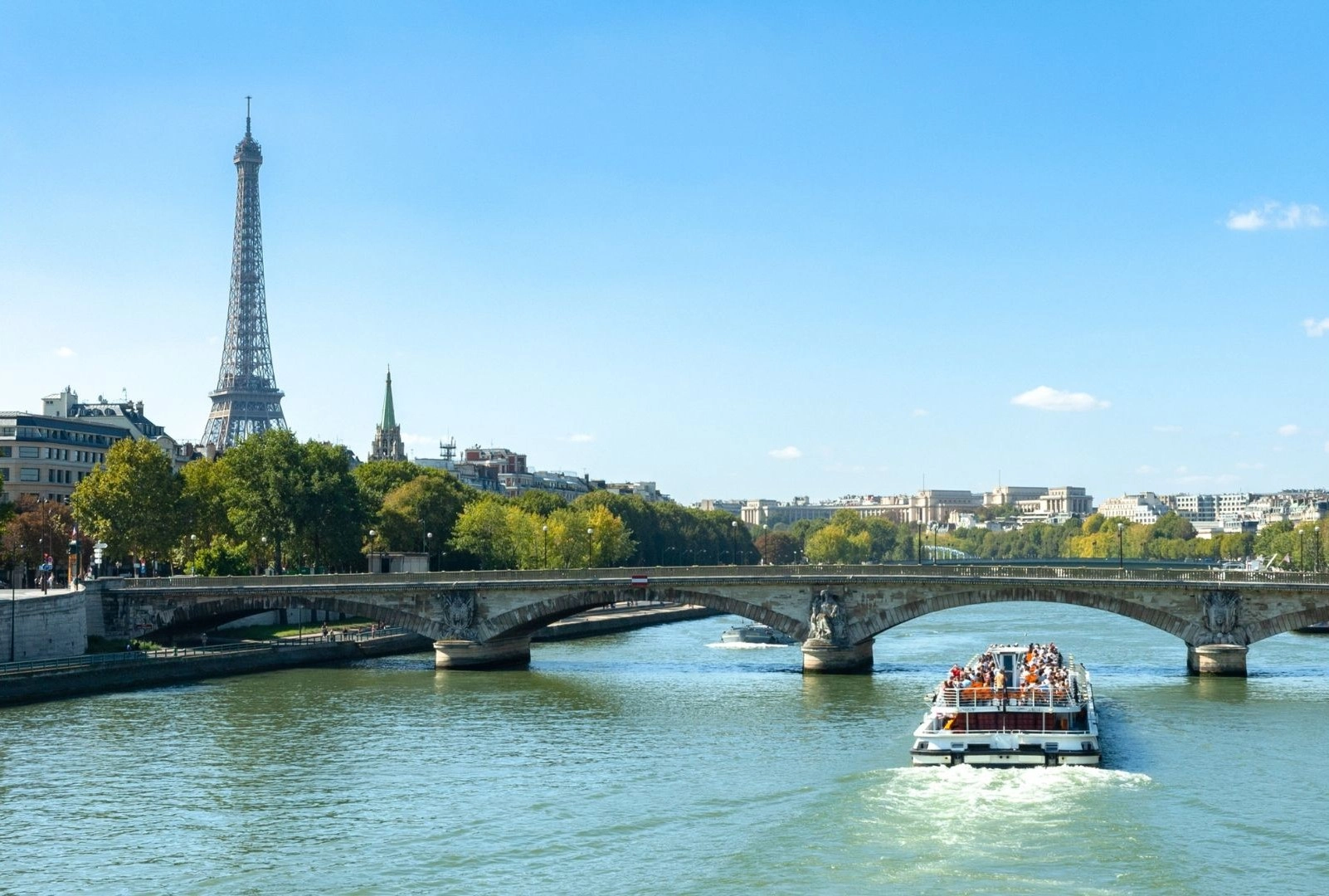 a boat on a river with a bridge and a tower in the background
