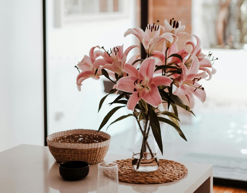 a vase of pink flowers and a bowl on a table