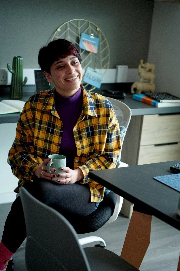 a woman sitting at a desk holding a mug