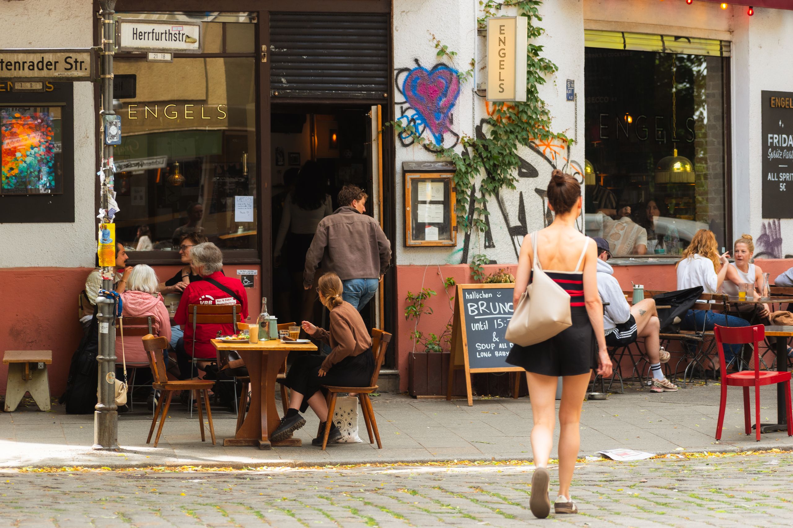 a woman walking down a sidewalk outside a restaurant