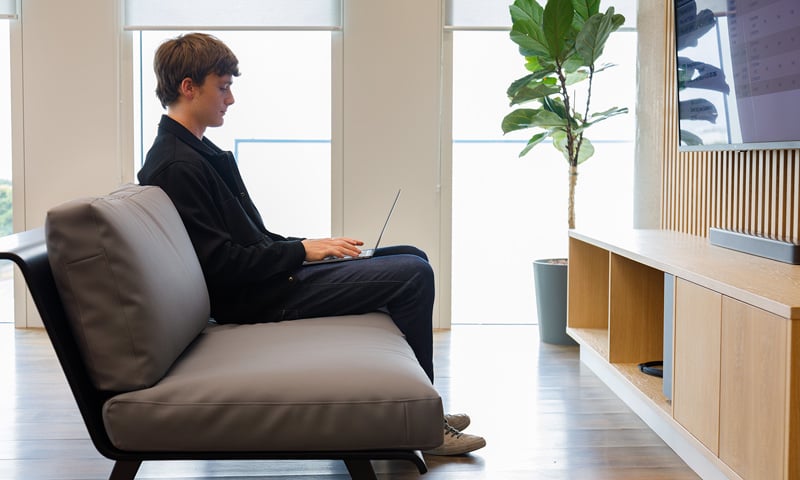 Young man sitting on a couch working on a computer