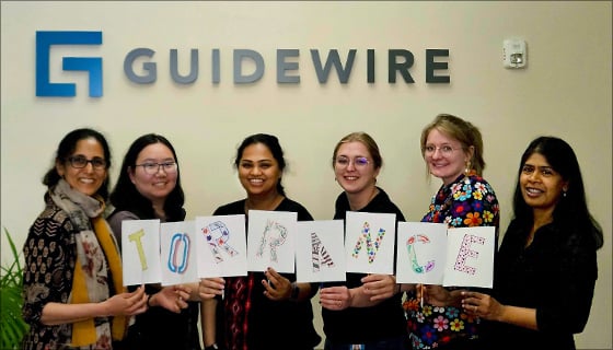 6 women in Guidewire office holding sign that says "Torrance"