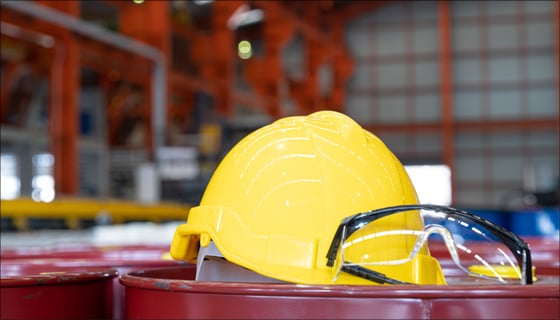 Safety helmet and goggles on barrel in a work environment