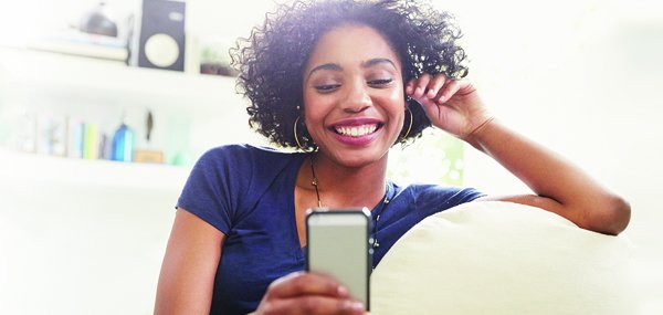 Lady smiling at cell phone in white room  600x285