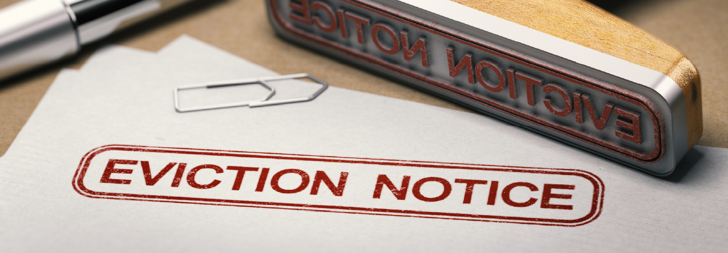 A desk with a pen, paperclip, a large stamp and a paper with the stamp that says EVICTION NOTICE.