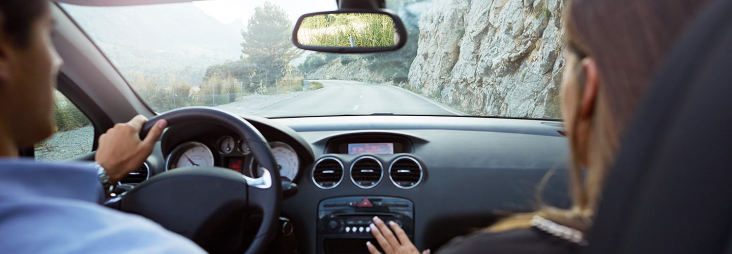 Two people traveling in a car along a mountain road