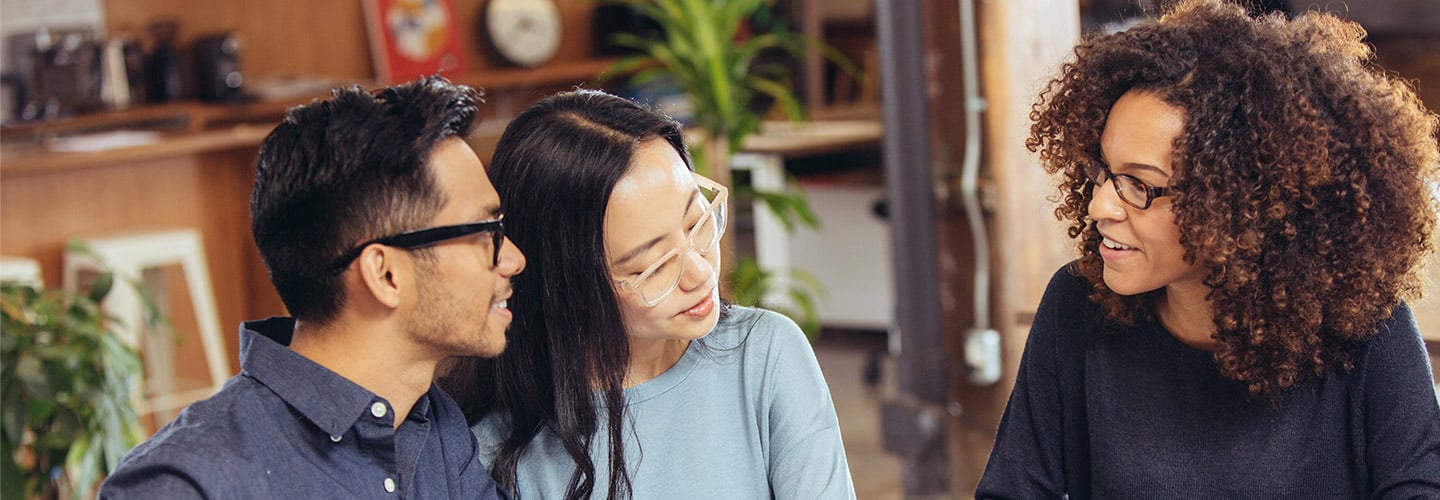 Three people sitting at a table going over paperwork