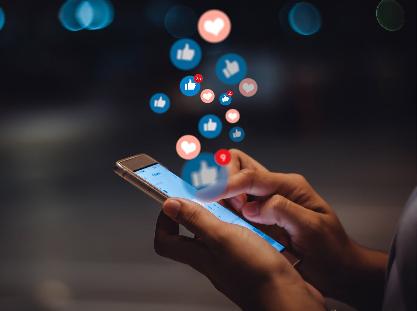 hands holding a cellphone with social media icons floating above the phone