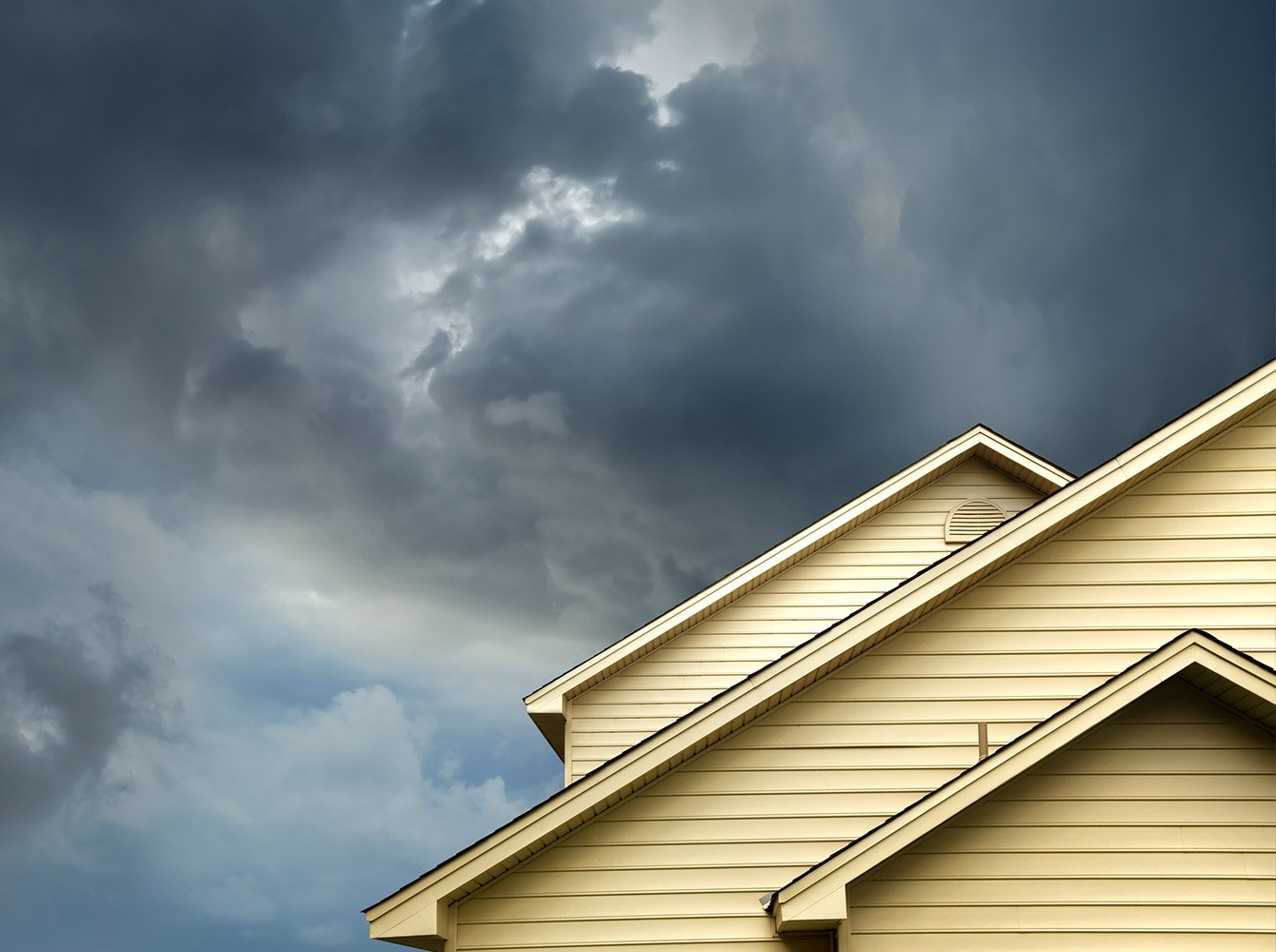 top of a house with dark storm clouds in the sky behind it