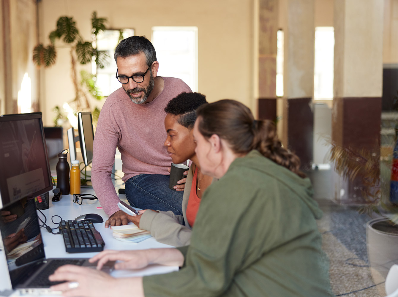 Employees gathered around a computer at a desk.